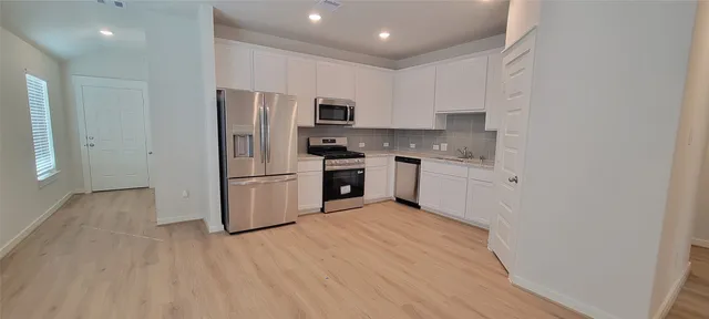 a kitchen with stainless steel appliances granite countertop a refrigerator a stove top oven a sink and dishwasher