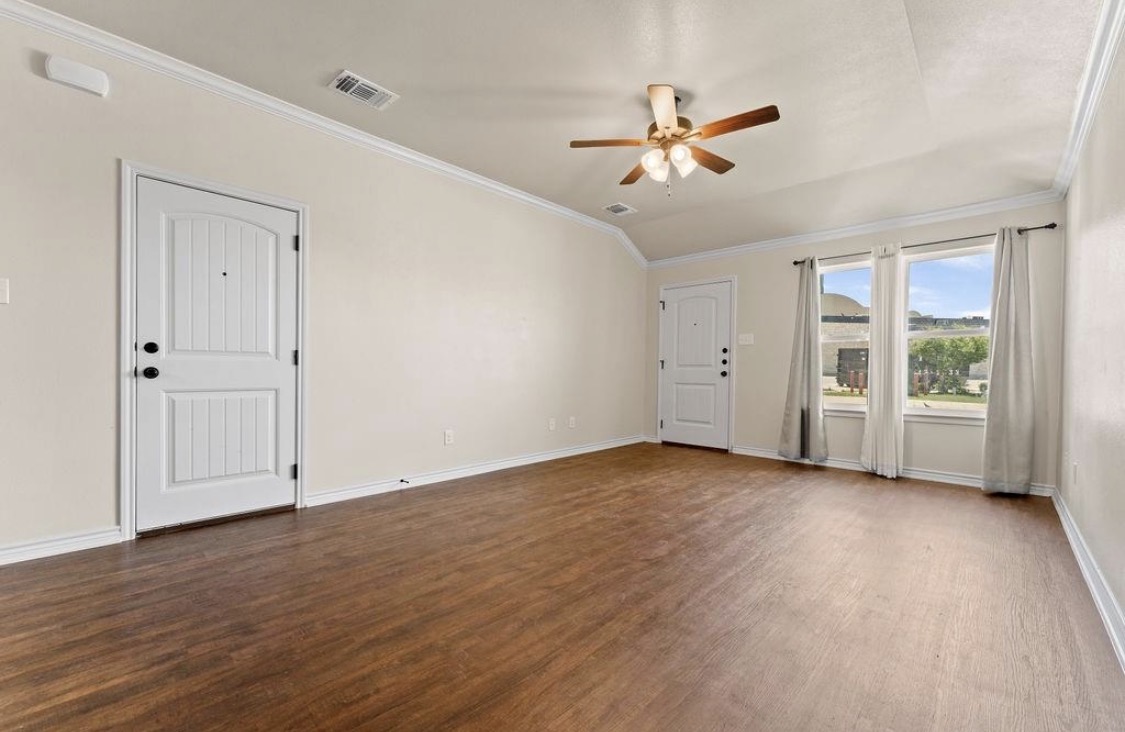 113 Calvin Smith Ln. Lane Jarrell, TX 76537 - Photo 2 of 16 an empty room with wooden floor chandelier fan and windows