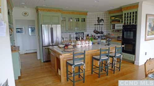 969 Center Hill Road Copake, NY 12516 - Photo 7 of 10 a kitchen with stainless steel appliances kitchen island granite countertop a refrigerator a stove a kitchen island with chairs and wooden floor