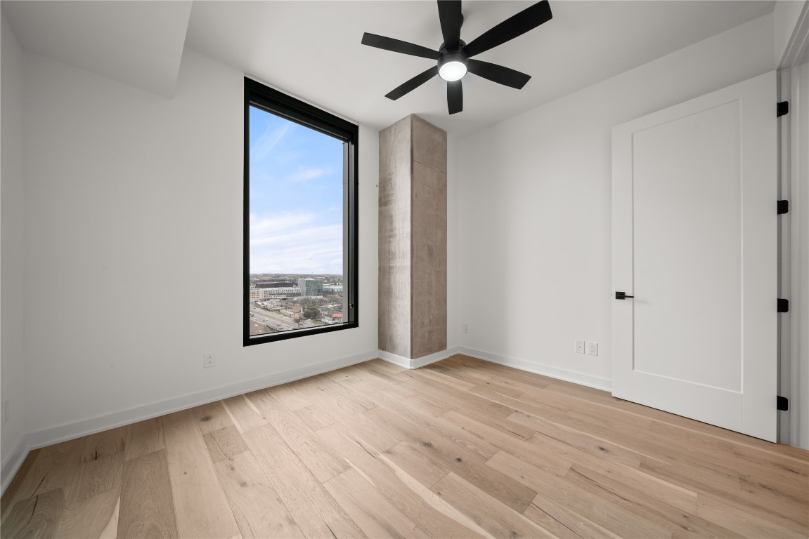 84 East Avenue, Unit 1708 Austin, TX 78701 - Photo 11 of 29 Unfurnished room featuring light wood-style flooring, a ceiling fan, and a city view
