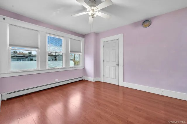 an empty room with wooden floor chandelier fan and windows