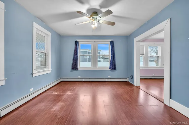 a view of an empty room with a window and wooden floor