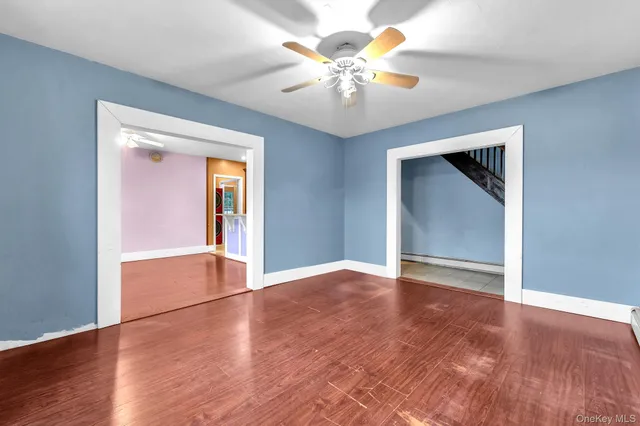 a view of an empty room with window and wooden floor
