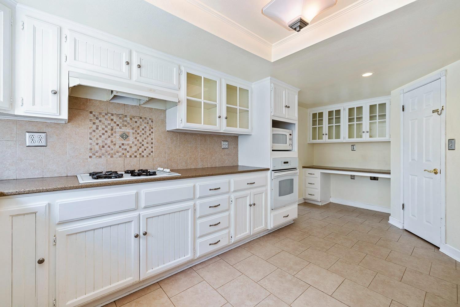 695 Monroe Street Coalinga, CA 93210 - Photo 14 of 44 a kitchen with granite countertop white cabinets and white stainless steel appliances