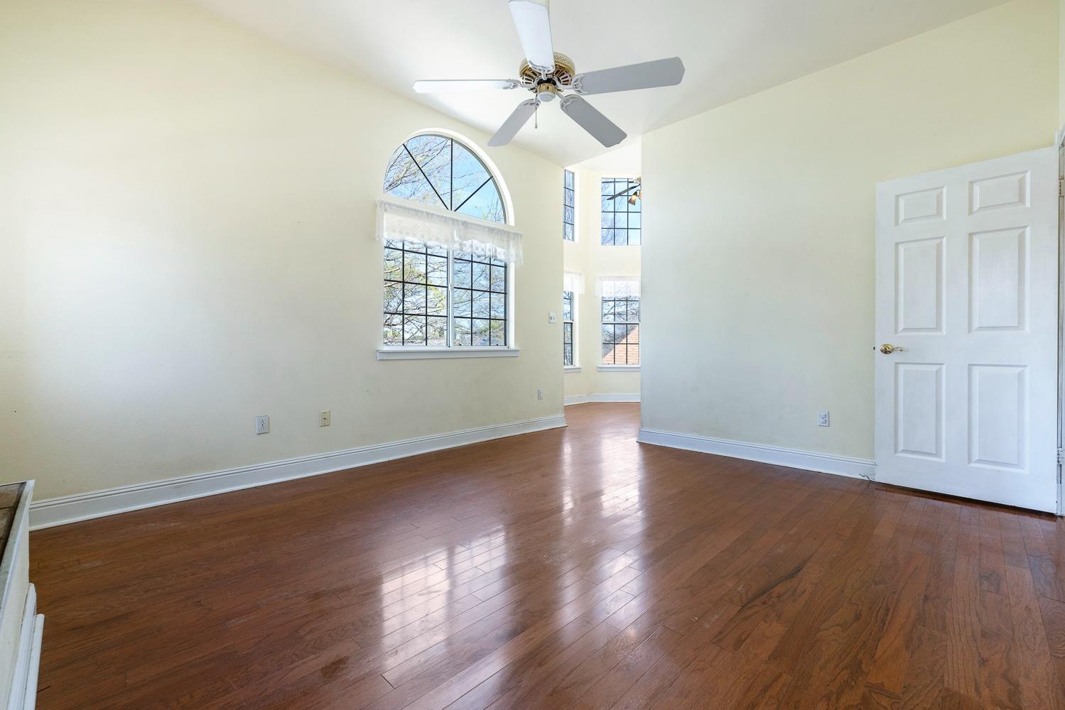695 Monroe Street Coalinga, CA 93210 - Photo 35 of 44 an empty room with wooden floor chandelier fan and windows
