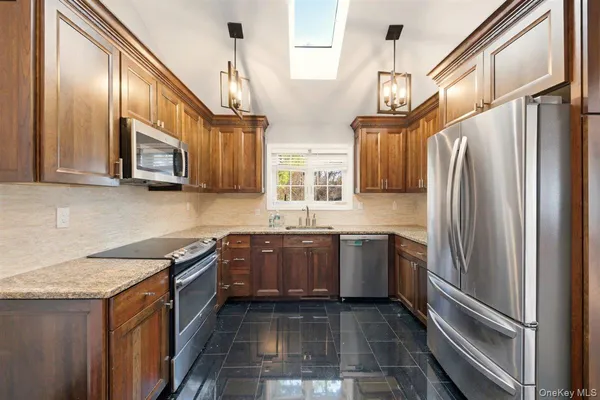 a kitchen with stainless steel appliances granite countertop a refrigerator a stove top oven and sink