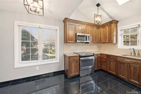 a kitchen with stainless steel appliances granite countertop a stove a sink and a microwave