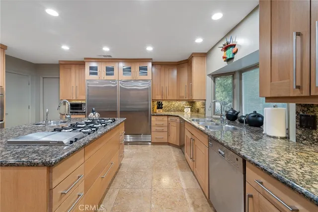 a kitchen with kitchen island granite countertop a sink and a refrigerator