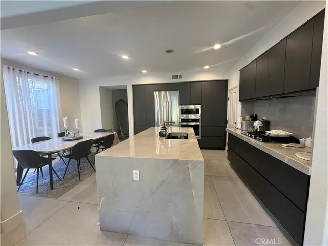 a large kitchen with kitchen island a sink table and chairs