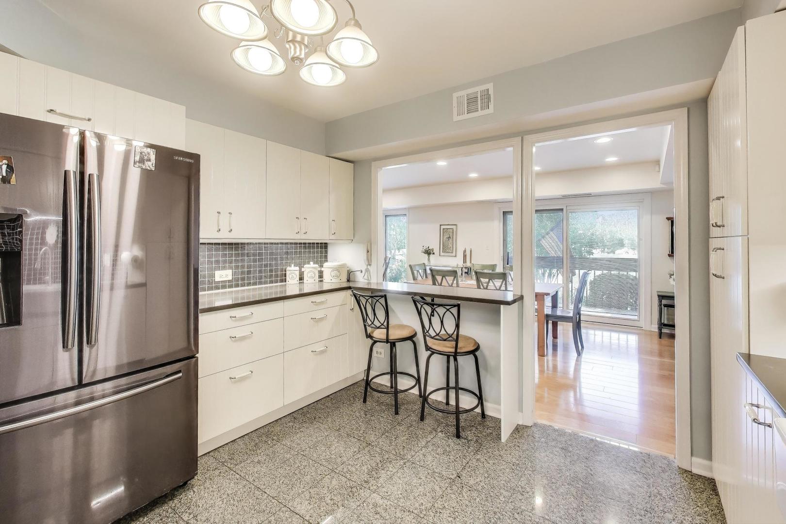 3955 Mission Hills Road, Unit D Northbrook, IL 60062 - Photo 10 of 26 a kitchen with stainless steel appliances granite countertop a refrigerator a sink a stove and white cabinets with wooden floor
