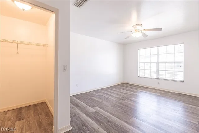 an empty room with wooden floor fan and windows