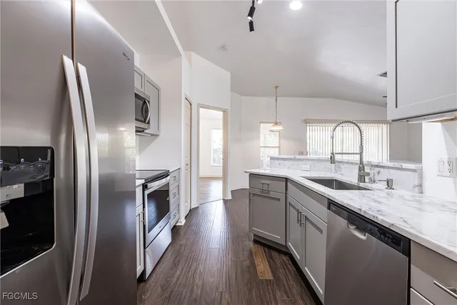 a kitchen with stainless steel appliances granite countertop a refrigerator a sink dishwasher a stove and white countertops with wooden floor