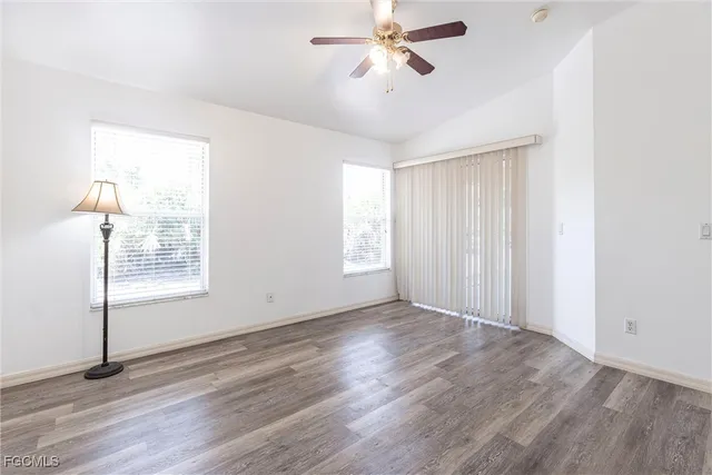 a view of an empty room with a window and wooden floor