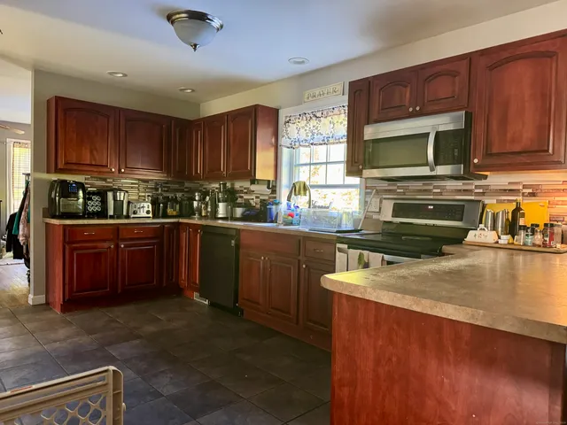 a kitchen with stainless steel appliances granite countertop wooden cabinets a stove top oven a sink and dishwasher
