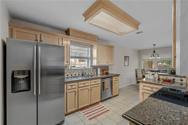 a kitchen with stainless steel appliances granite countertop a refrigerator a stove and a sink with cabinets