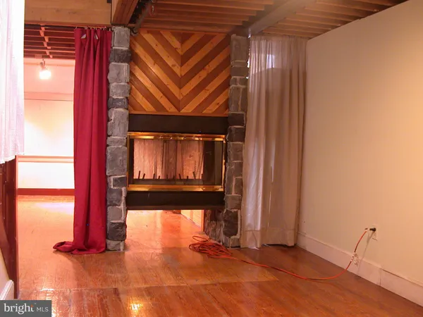 a view of an empty room with wooden floor and stairs