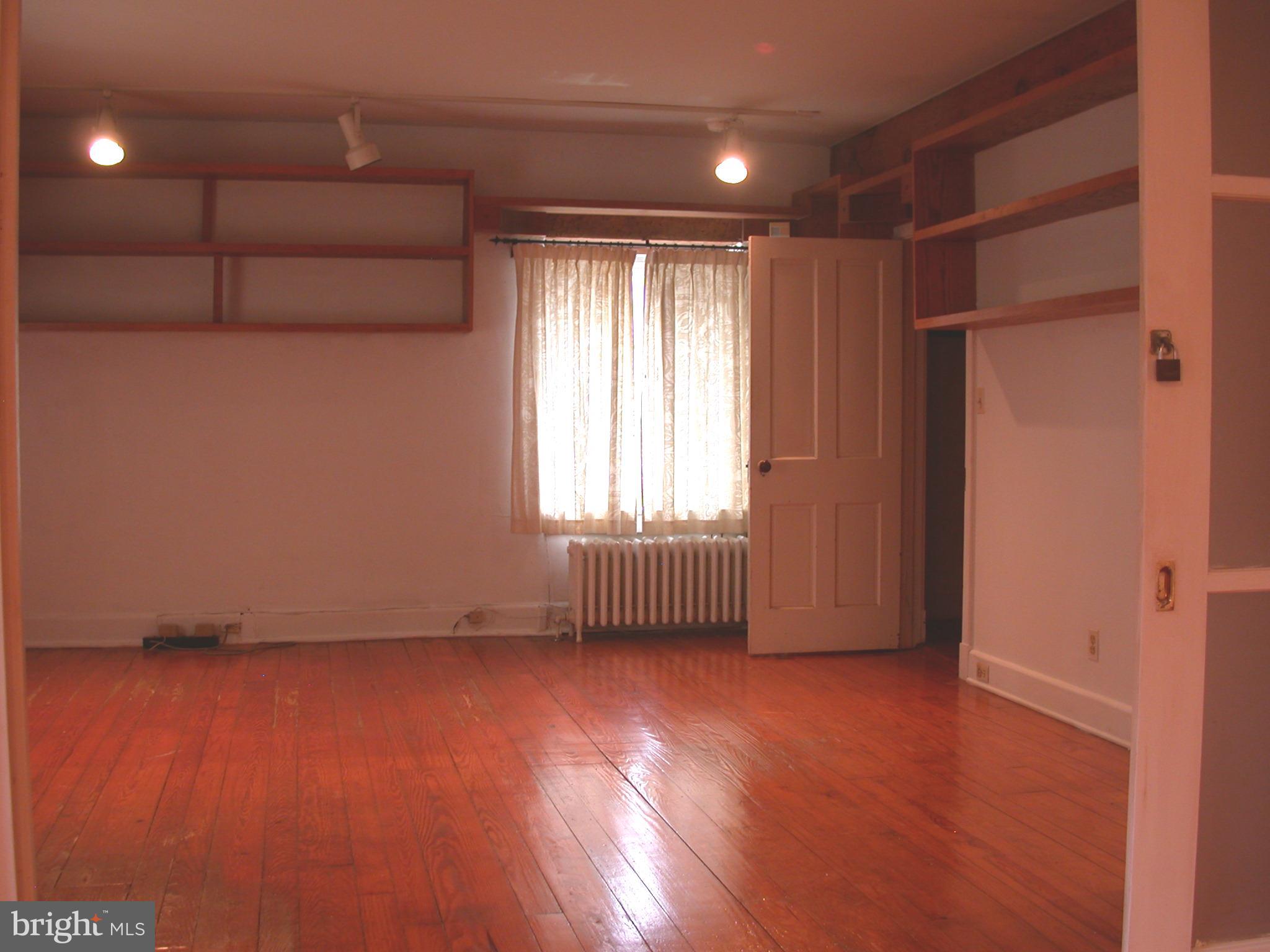 2423 Pickwick Road Baltimore, MD 21207 - Photo 31 of 34 an empty room with wooden floor and windows with curtains