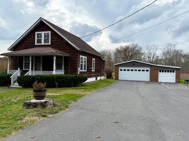 a view of a house with a yard potted plants and a bench