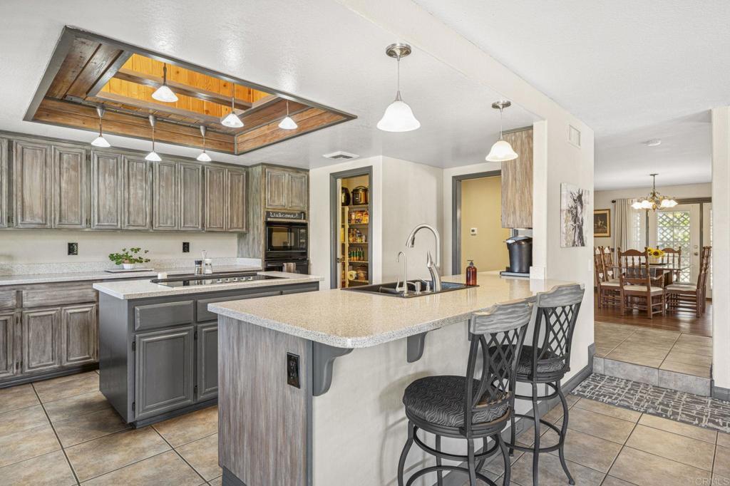 3223 Olive Hill Road Fallbrook, CA 92028 - Photo 11 of 64 a kitchen with stainless steel appliances granite countertop a stove top oven a sink a dining table and chairs with wooden floor