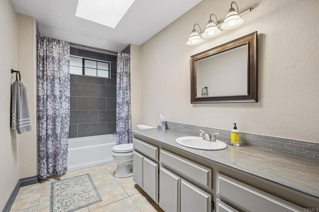 3223 Olive Hill Road Fallbrook, CA 92028 - Photo 16 of 64 a bathroom with a granite countertop sink a toilet a mirror and shower