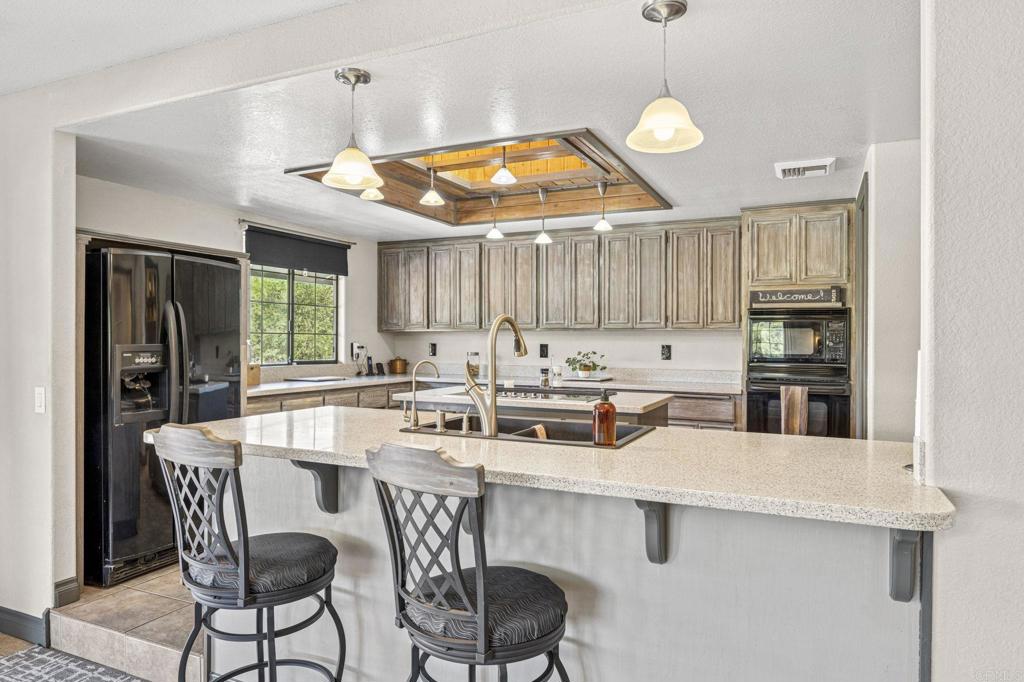 3223 Olive Hill Road Fallbrook, CA 92028 - Photo 10 of 64 a kitchen with stainless steel appliances a table chairs and a refrigerator
