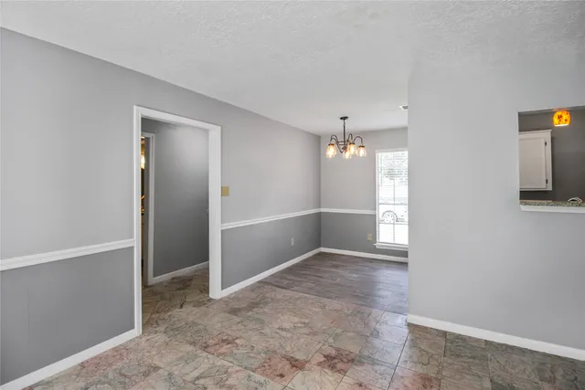 an empty room with chandelier fan and hallway
