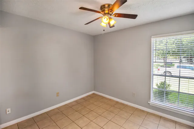 an empty room with windows and chandelier fan