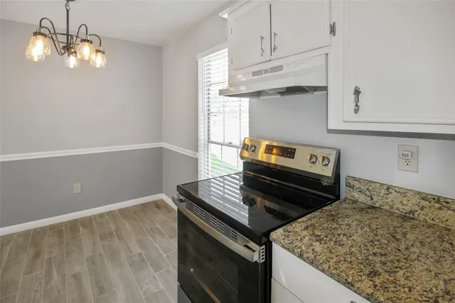 a kitchen with granite countertop a stove and a white cabinets