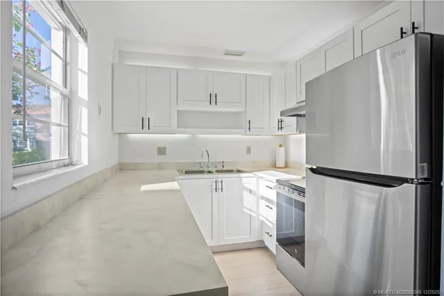 a kitchen with stainless steel appliances a refrigerator sink and white cabinets