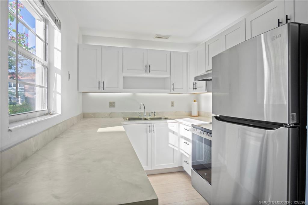 a kitchen with stainless steel appliances a refrigerator sink and white cabinets