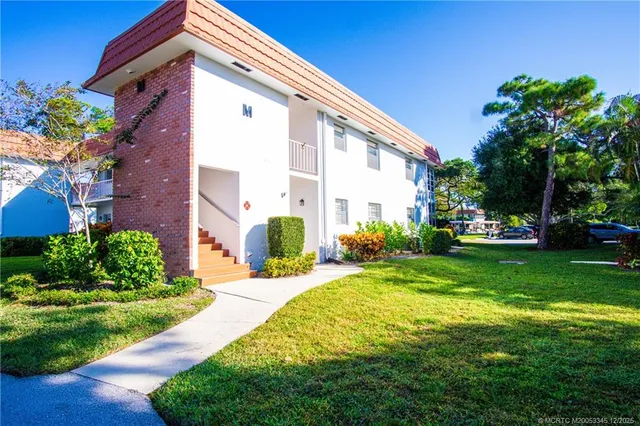 a front view of a house with garden and trees