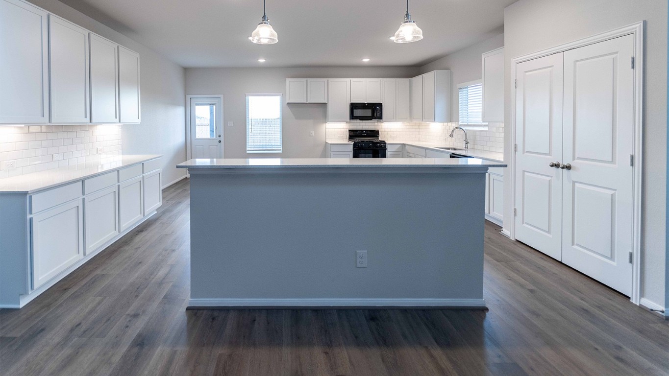 280 Yosemite Drive Kyle, TX 78640 - Photo 11 of 18 a large kitchen with cabinets wooden floor and stainless steel appliances