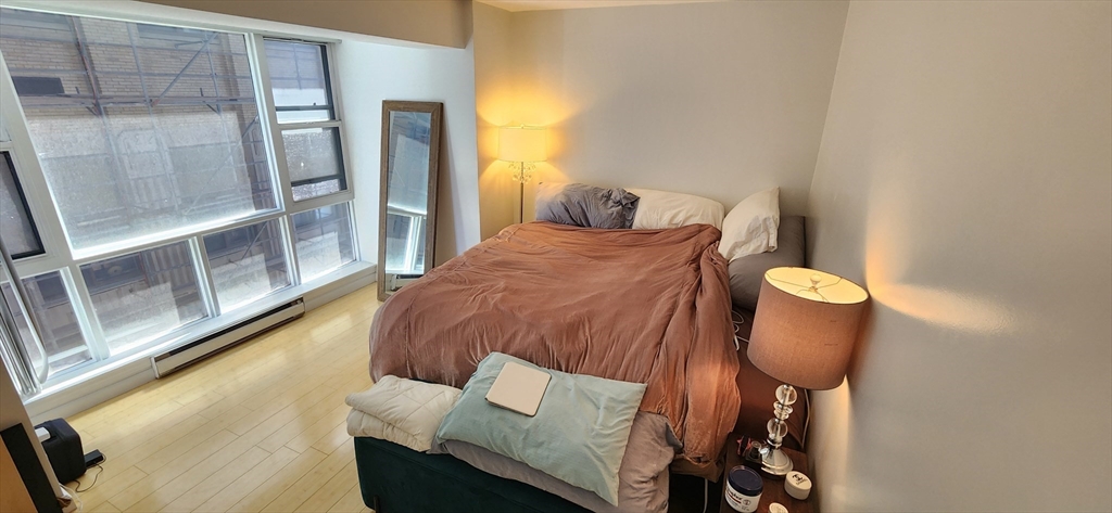 170 Tremont Street, Unit 606 Boston, MA 02111 - Photo 5 of 19 a bedroom with a bed and wooden floor
