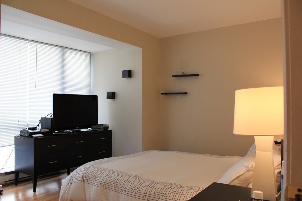 170 Tremont Street, Unit 606 Boston, MA 02111 - Photo 10 of 19 a bedroom with a bed and a flat tv screen on a dresser