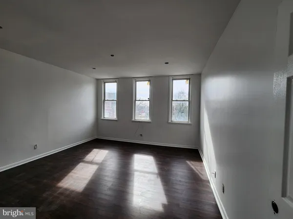 a view of an empty room with wooden floor and closet