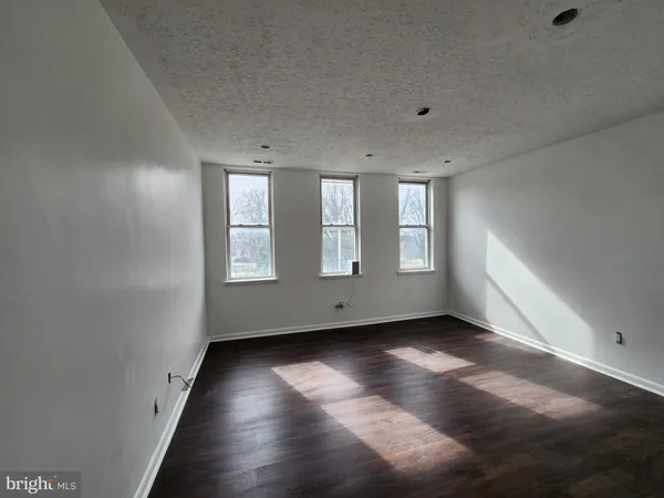 a view of an empty room with wooden floor and closet