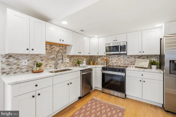 a kitchen with granite countertop white cabinets sink and stainless steel appliances