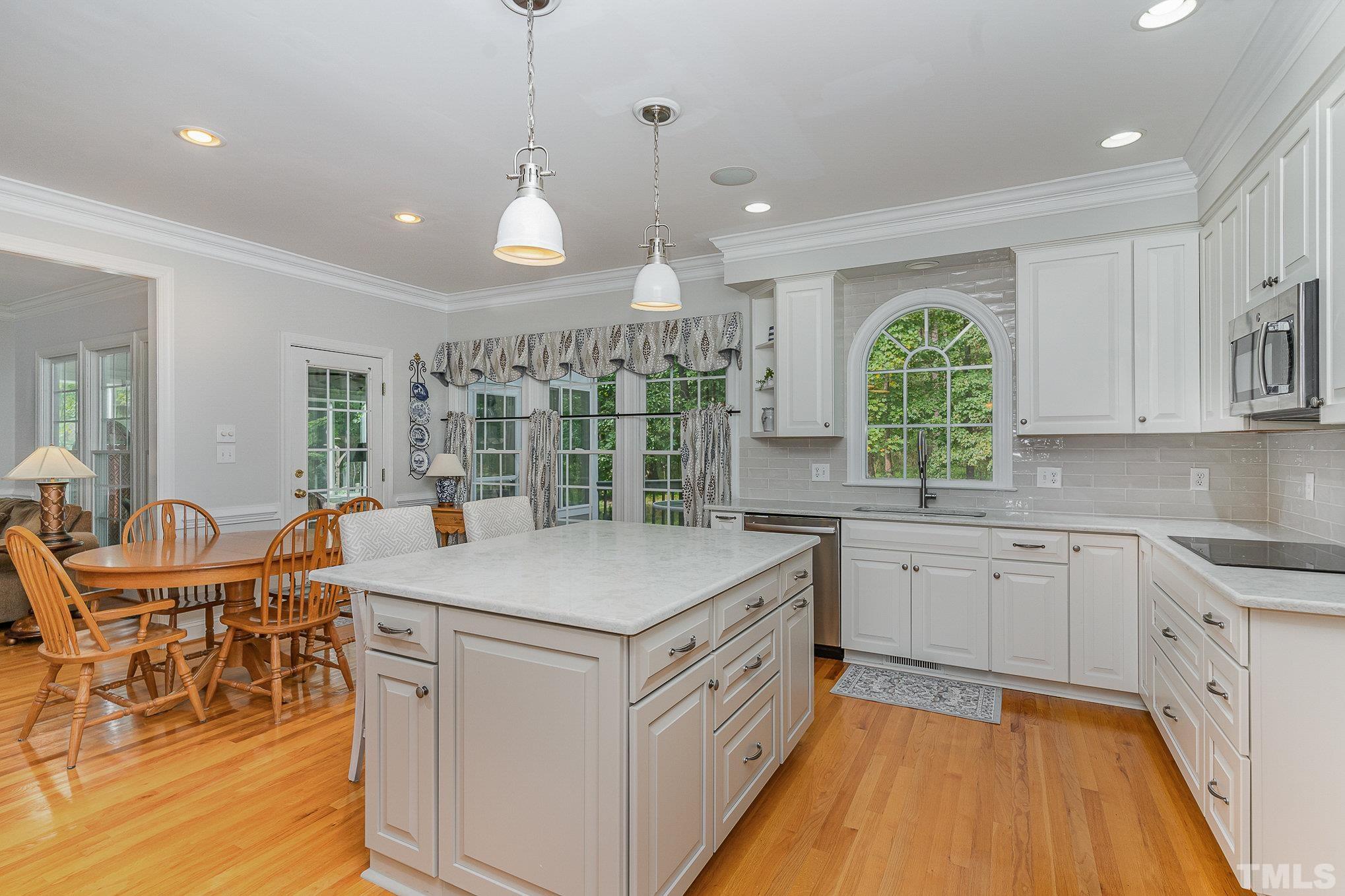 9409 Stone Mountain Road Raleigh, NC 27613 - Photo 15 of 53 a open kitchen with stainless steel appliances granite countertop a stove top oven a sink dishwasher a dining table and chairs with wooden floor