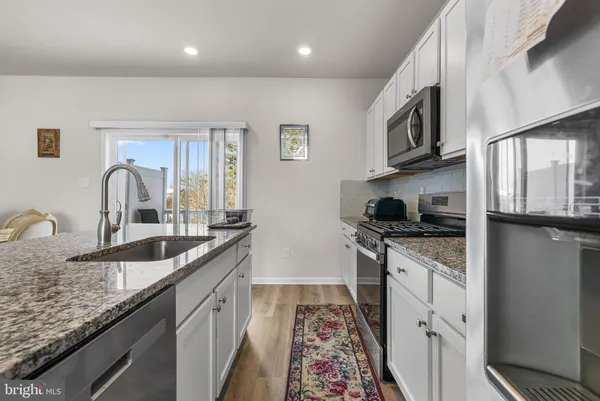a kitchen with stainless steel appliances granite countertop a sink dishwasher stove top oven and cabinets with wooden floor