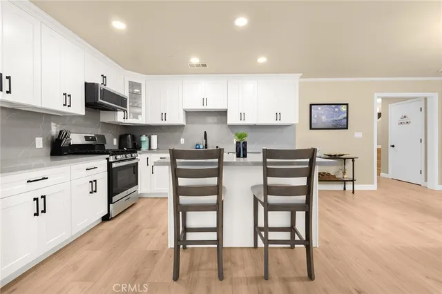 a kitchen with stainless steel appliances kitchen island granite countertop a stove top oven a sink a dining table and chairs with wooden floor