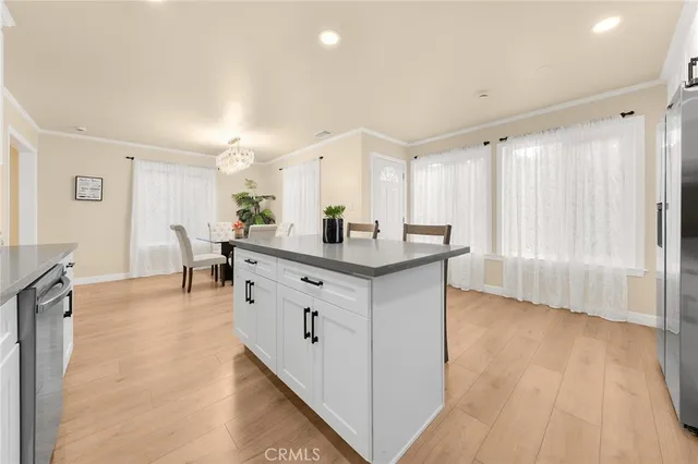 a kitchen with stainless steel appliances granite countertop a coffee maker a sink a refrigerator and white cabinets with wooden floor