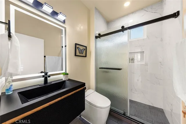a bathroom with a sink a toilet a mirror and shower