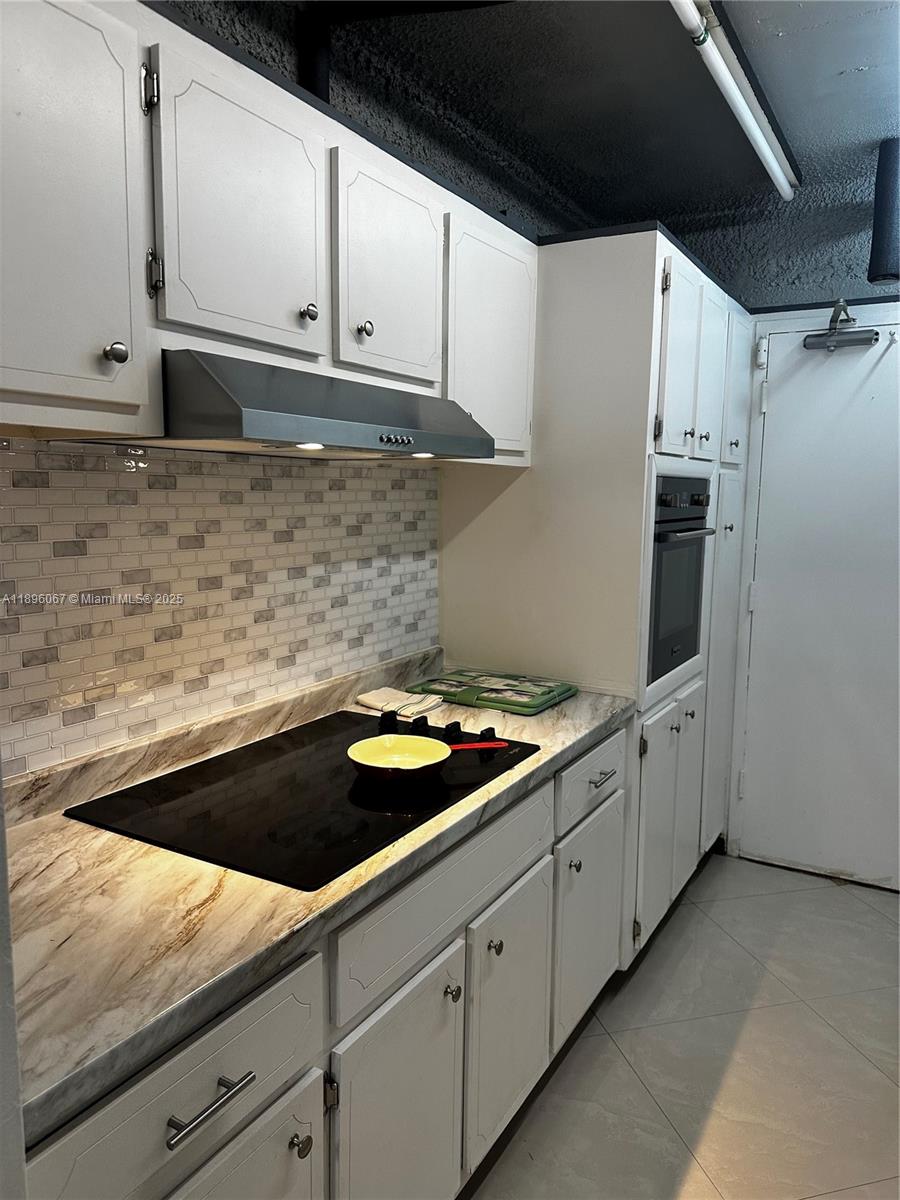 1200 West Avenue, Unit 914 Miami Beach, FL 33139 - Photo 21 of 38 a kitchen with granite countertop white cabinets and white appliances