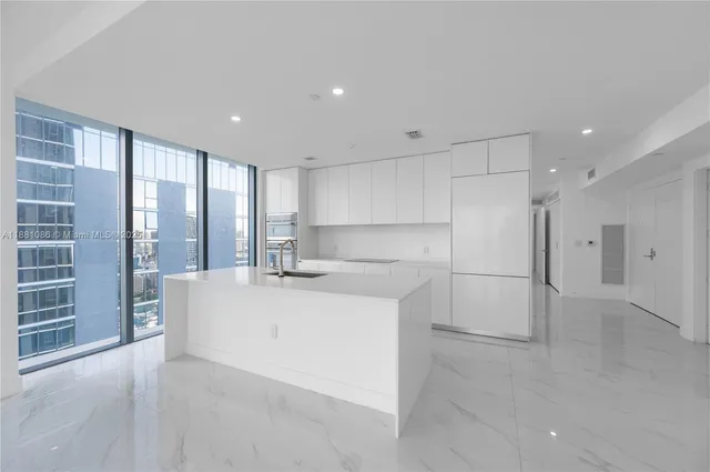 a large white kitchen with a sink and refrigerator