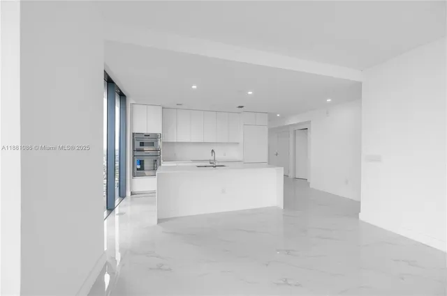 a large white kitchen with a refrigerator a stove top oven and white kitchen