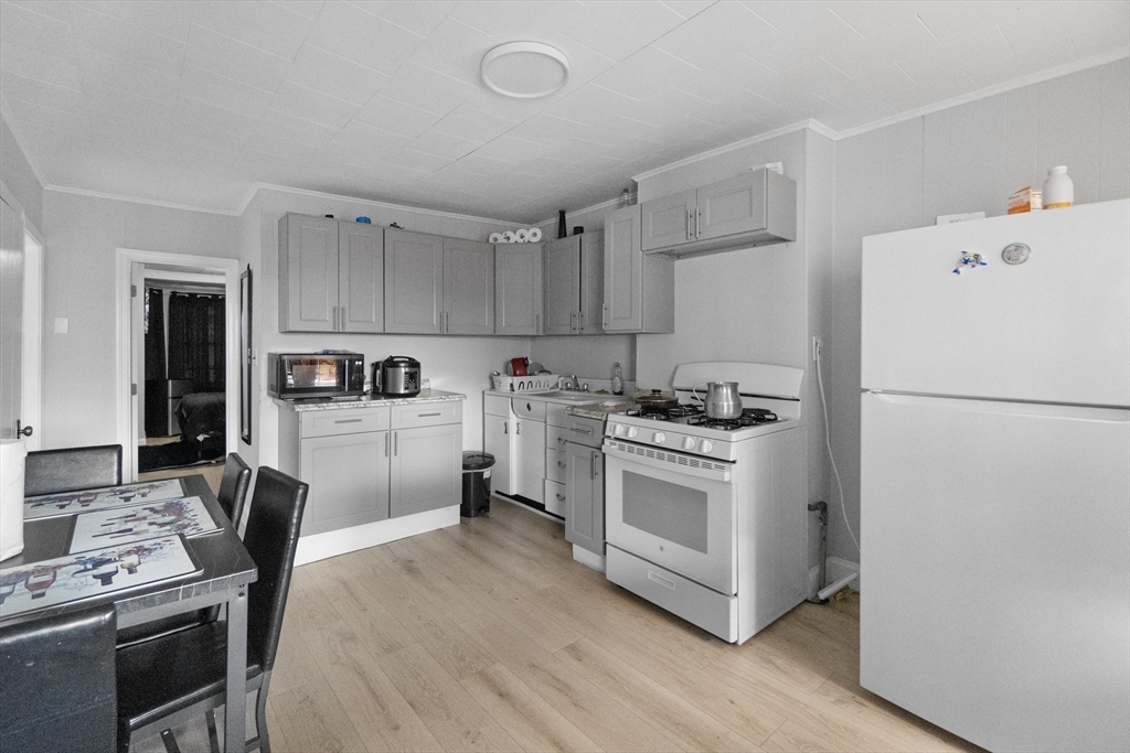 225 London Street Boston, MA 02128 - Photo 3 of 10 a kitchen with a refrigerator a stove top oven a sink dishwasher and white cabinets with wooden floor