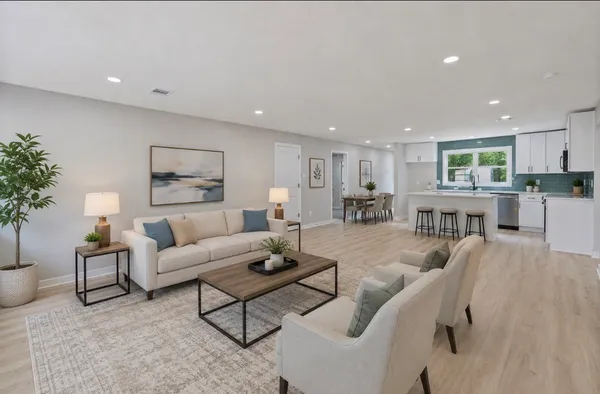 a living room with furniture kitchen view and a potted plant