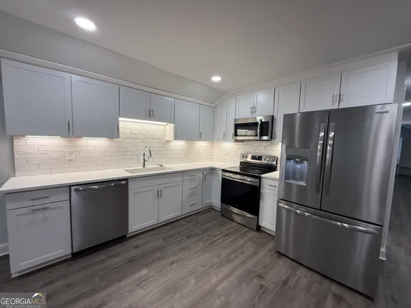 a kitchen with granite countertop stainless steel appliances a refrigerator a sink a stove and cabinets