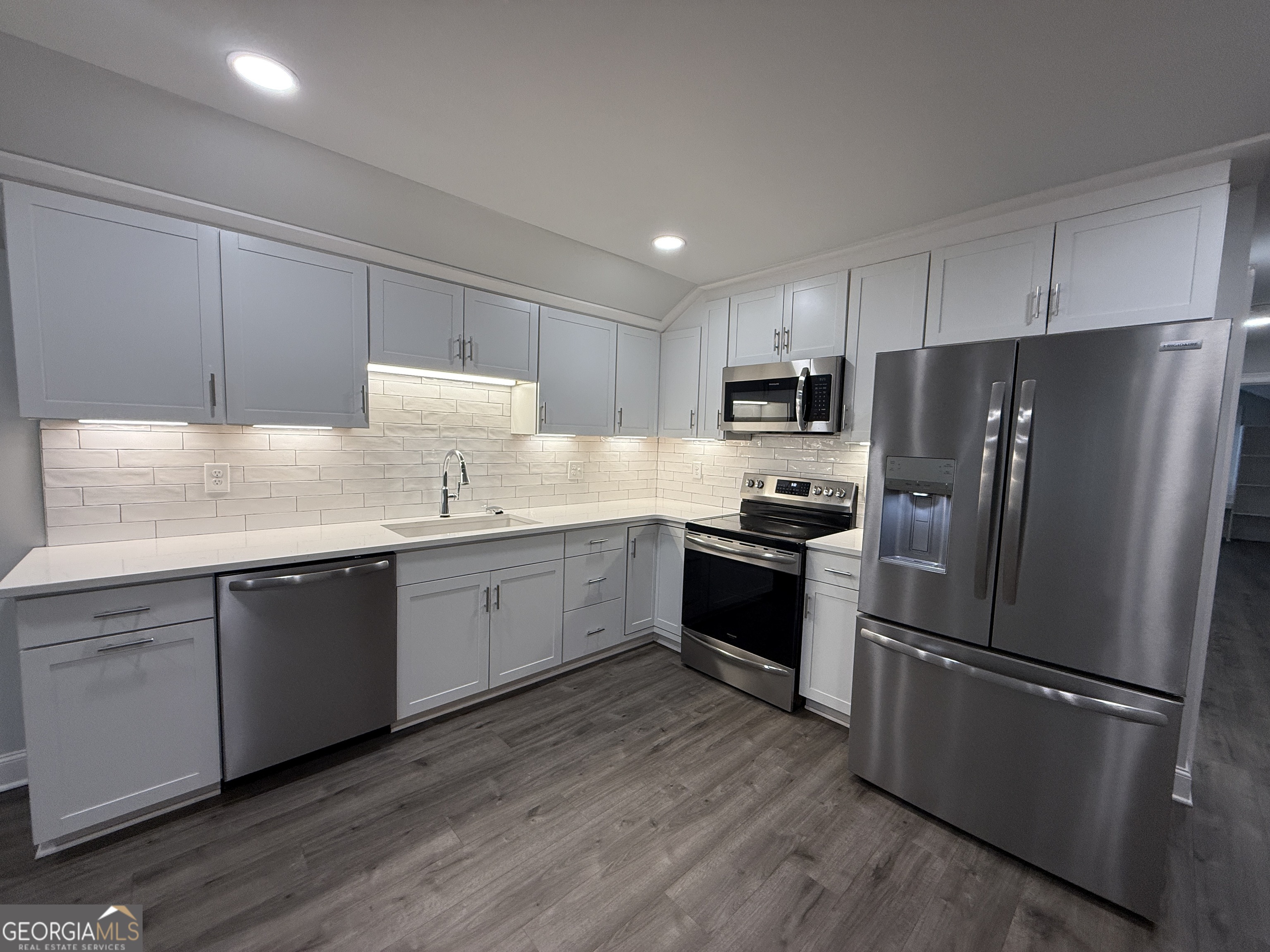 a kitchen with granite countertop stainless steel appliances a refrigerator a sink a stove and cabinets