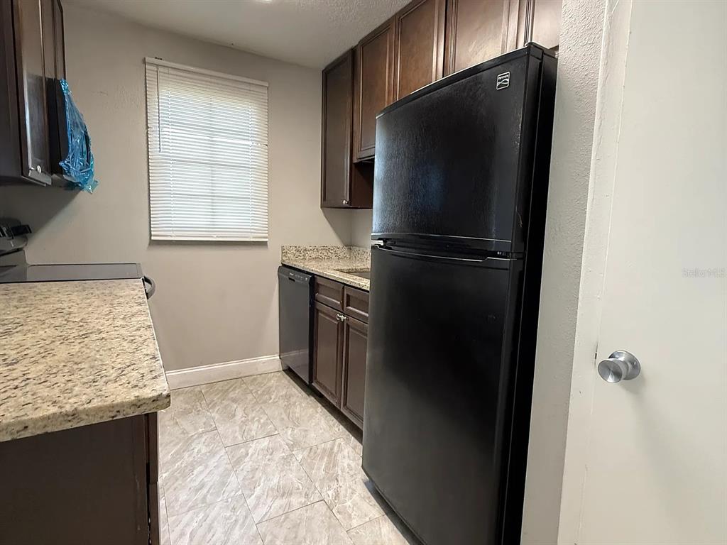 2789 L B McLeod Road, Unit 2789B Orlando, FL 32805 - Photo 4 of 8 a kitchen with stainless steel appliances granite countertop a refrigerator and a sink